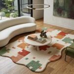 Modern color block rug styled in a contemporary living room with curved cream sofa, natural wood flooring and green accent chair